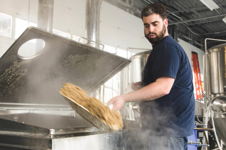 Thomas Owens shoveling some spent grain while brewing at Great Flats